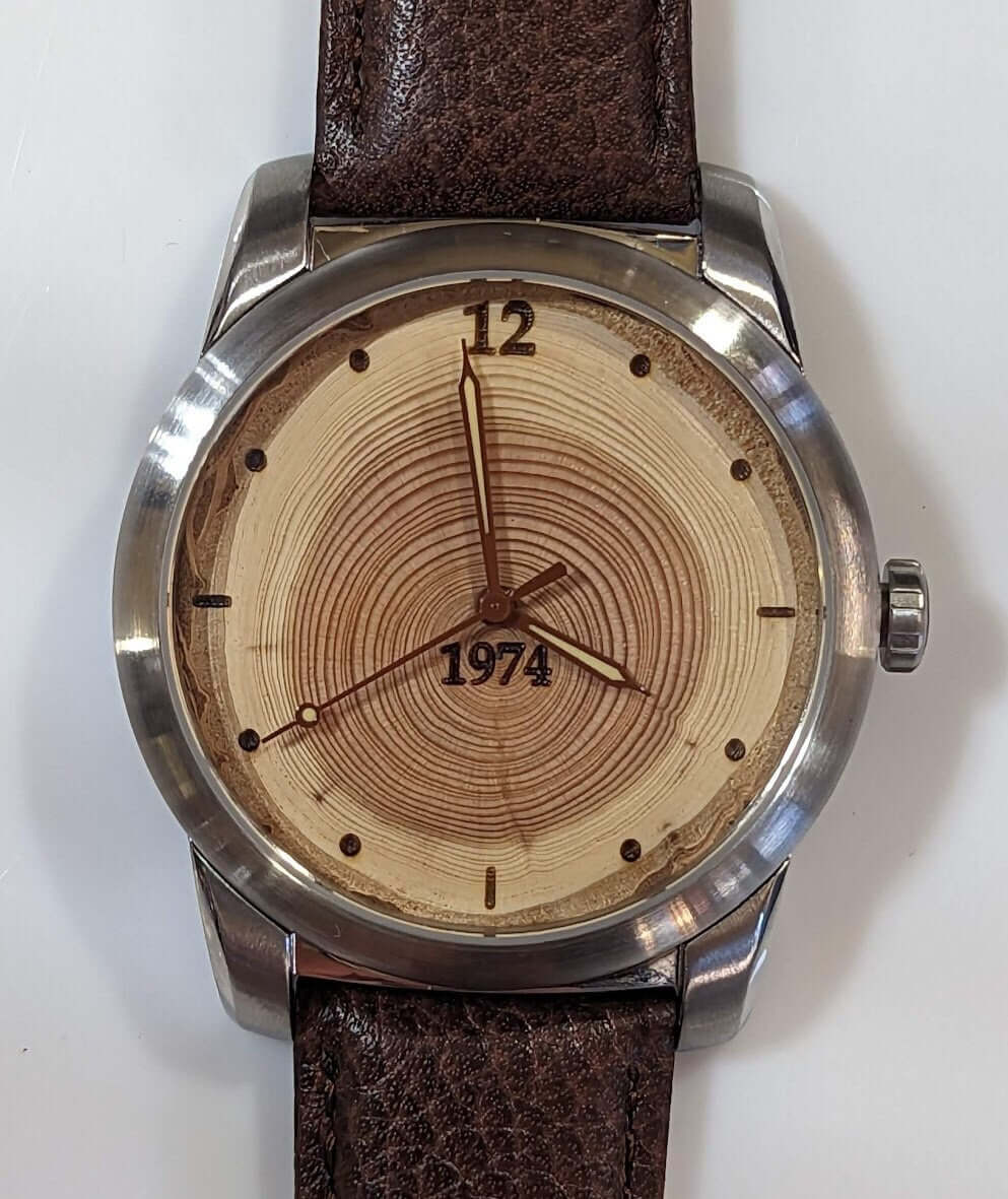 Tree ring watch celebrating 50 years with a wooden dial showing annual rings and leather strap.