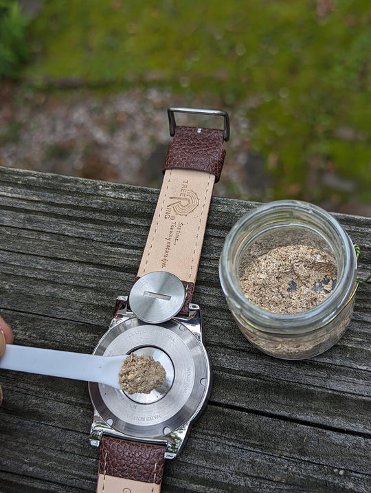 Filling the Tree Ring Urn Watch with a small compartment for ashes, featuring a brown leather strap.