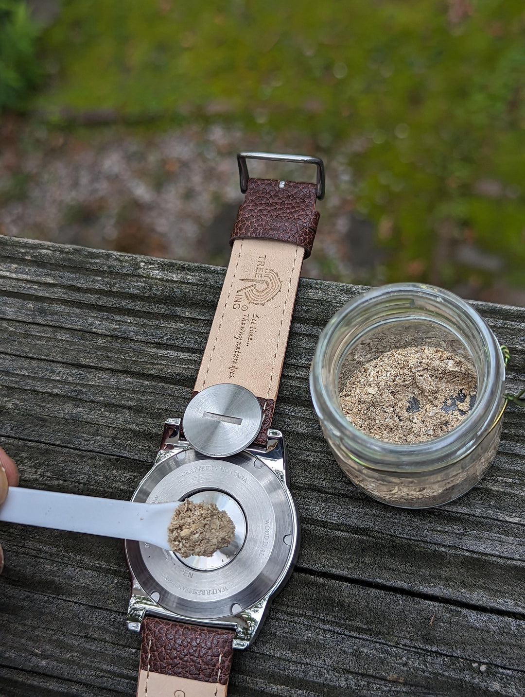 Tree Ring Memorial Pet Watch with compartment for pet cremation remains, shown with jar of ashes.