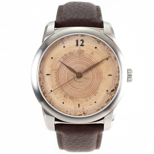 Classic wood watch with tree ring dial, featuring annual rings and brown leather strap.